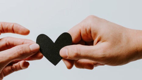 Hands exchanging a black paper heart