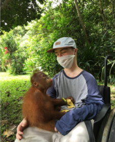 Photo of Benni with a monkey in his lap.